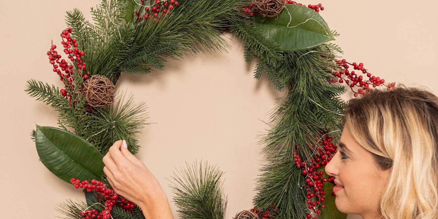 Weihnachtskranz Giulia Grillo mit roten Beeren, an der Wand aufgehängt